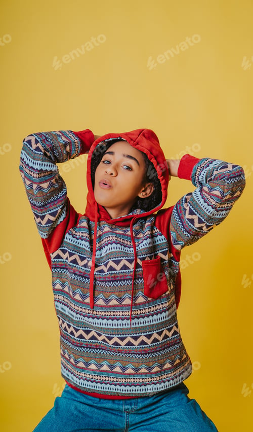 Preview: A Portrait Of A Cheerful Hispanic Female With Curly Hair Wearing A Hoodie And Jeans Against A