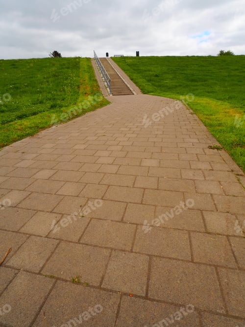 Preview: A Vertical Shot Of A Walkway Made Of Stone Surrounded By Green Grass