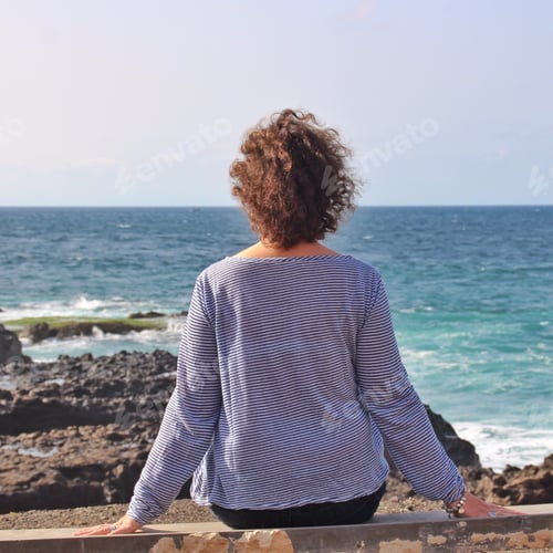Preview: A Lonely Female Sitting On A Rock And Enjoying The Beautiful View Of The Sea