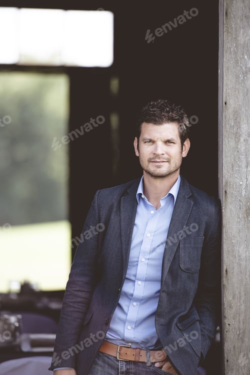 Preview: A Vertical Shot Of A Well-Dressed Male Leaning Against The Wall And Looking At The Camera