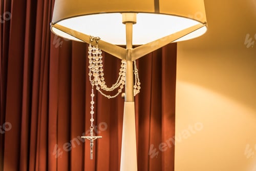 Preview: A Vertical Shot Of A Bedside Lamp And A Beautiful Silver Cross Hanging On It And Shining Under The