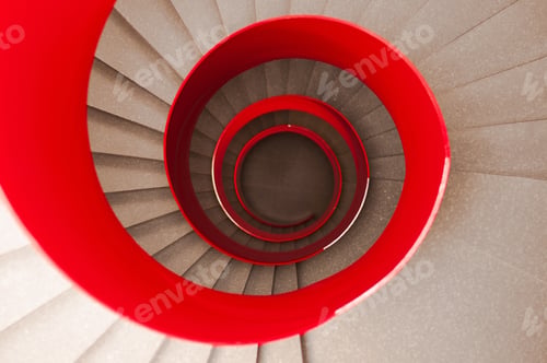 Preview: A High Angle Shot Of A Winding Staircase With A Red Railing