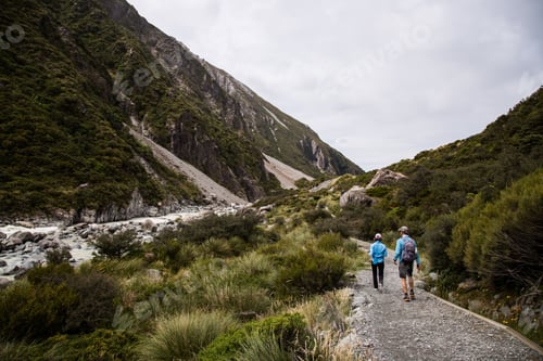 Preview: A View Of Two People Hiking In The Tree-Covered Cliffs With A River Between The Cliffs