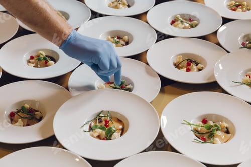 Preview: A Cook Adding Ingredients On A Dish Filled In White Serving Plates In A Restaurant