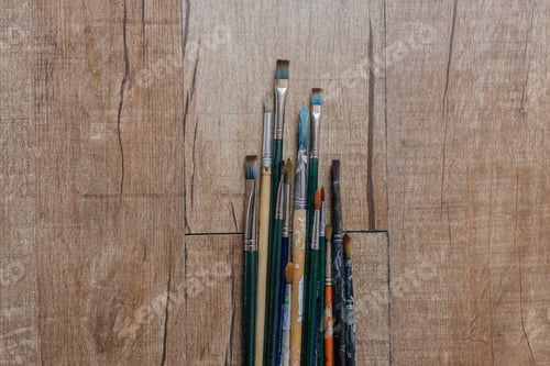 Preview: A Top View Of Different Color-Stained Paintbrushes On A Wooden Surface