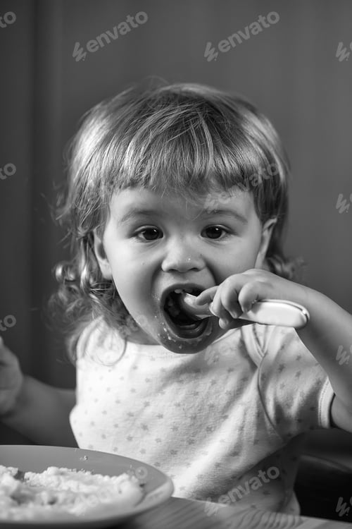 Preview: Closeup Portrait View Of One Adorable Cute Small Baby Boy With Blonde Hair Eating Healthy Food Of