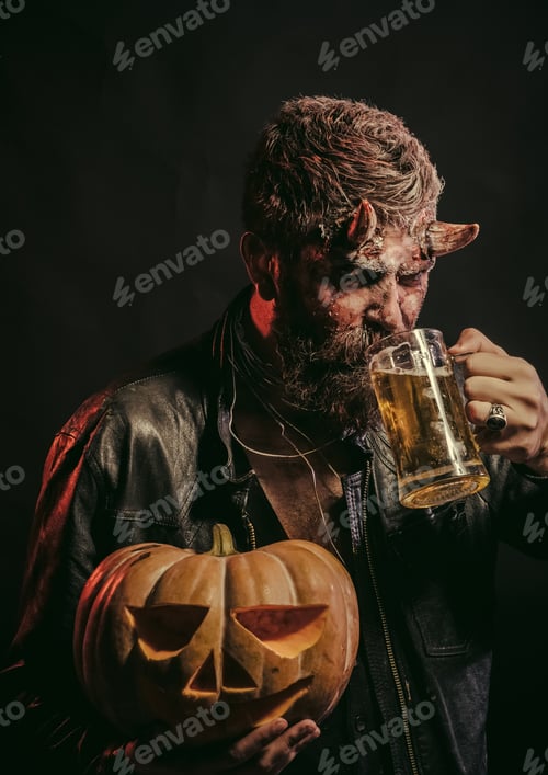 Preview: Halloween Man With Satan Horns Hold Pumpkin. Bad Habits And Addiction Concept. Devil With Glass