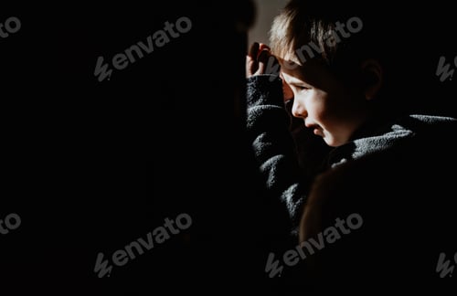 Preview: Little Boy Looking Outside A Window Isolated In Black Background