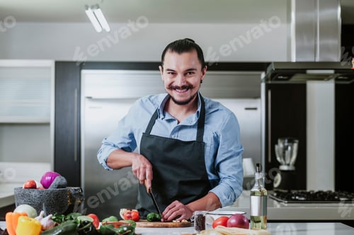 Preview: Latin Man Cooking At Home Preparing Salad Or Mexican Sauce In Kitchen At Home In Mexico City