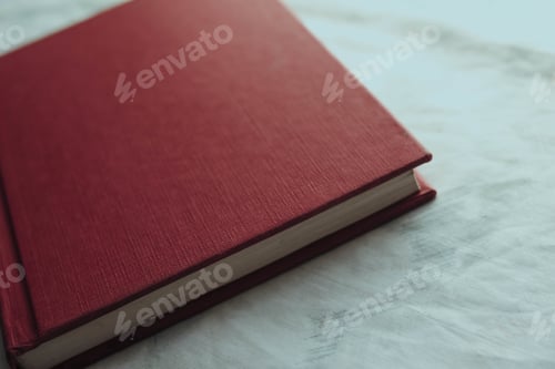 Preview: A High Angle View Of A Book With A Red Hardcover On The Table Under The Lights