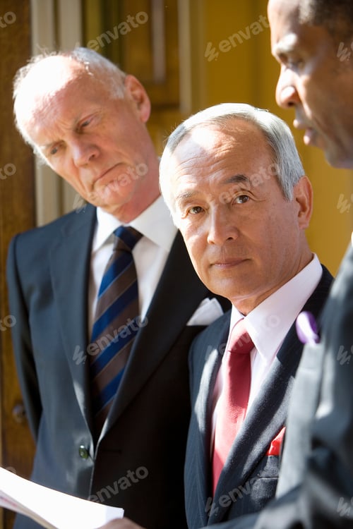 Preview: Senior Businessman In A Suit Standing With His Colleagues And Looking At The Camera With A Serious