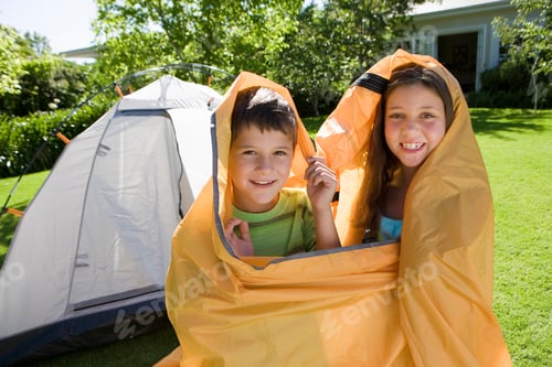 Preview: Horizontal Shot Of A Brother And Sister Wrapped In An Orange Outer Tent Canvas Smile At The Camera