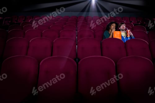 Preview: Horizontal Shot Of A Young Couple In An Empty Cinema Hall With Drink And Popcorn In Hand.