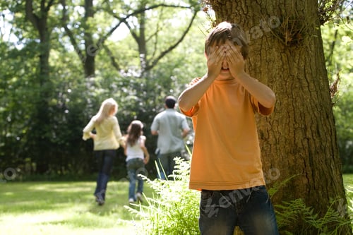 Vista previa: Family Of Four Playing Hide And Seek In The Forest With The Boy In The Foreground Covering Eyes.