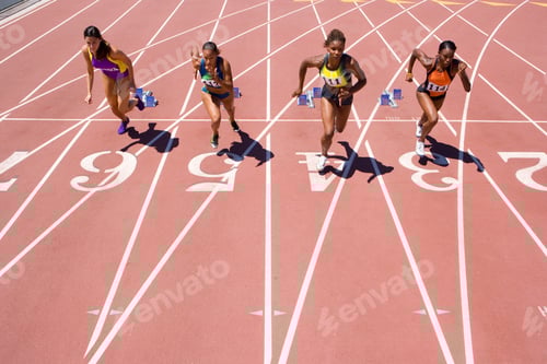 Preview: Female Athletes Setting Off From Their Starting Blocks At The Start Of A Sprint Race At An