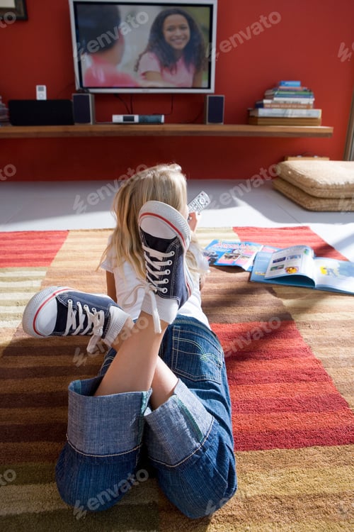 Preview: Little Girl Lying Down On The Rug In Front Of A Television With An Open Magazine Lying On The Floor