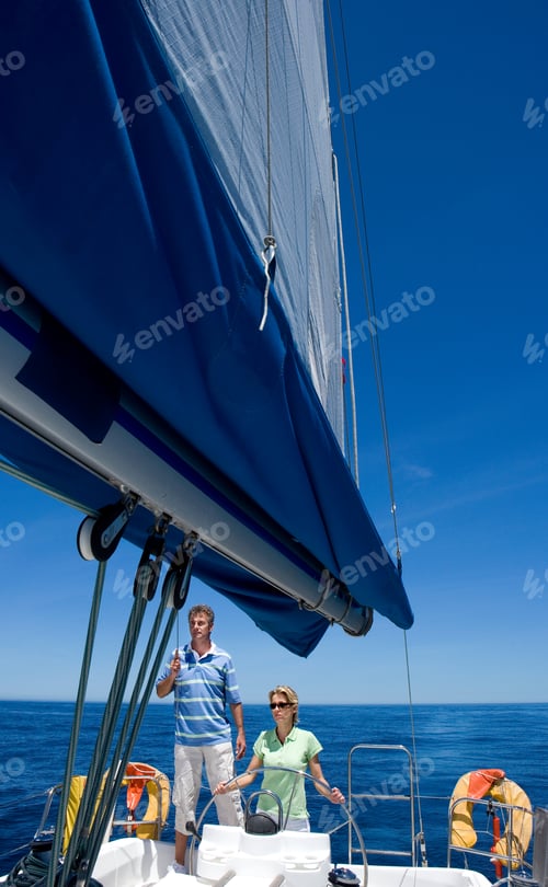 Preview: Vertical Shot Of A Young Couple Standing At The Helm Of Sailing Boat Out At Sea.