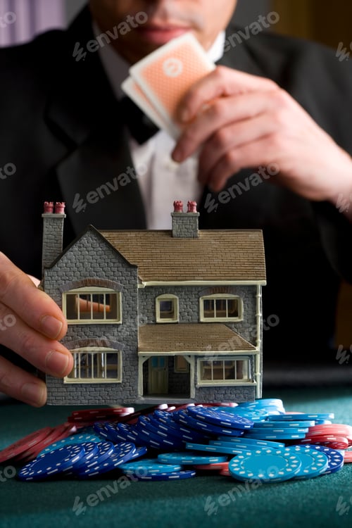Preview: Vertical Close Up Of A Man Placing A Model House On A Pile Of Gambling Chips On The Table During A