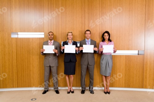 Preview: Horizontal Shot Of A Four Business Colleagues In A Row By The Wall Holding Paper To Their Chests