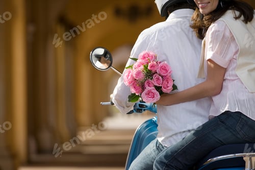 Preview: Rearview Of A Young Couple Riding On A Motor Scooter Near Colonnade With The Woman Holding Bouquet