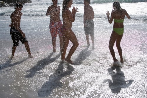 Preview: Group Of Teenagers Playing In The Water At The Beach Splashing Water On Each Other.