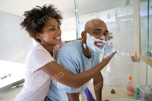 Preview: Horizontal Shot Of A Young Woman In The Bathroom With Her Husband Applying Shaving Foam To His Face