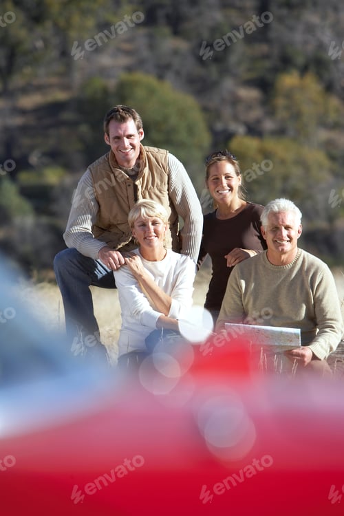 Preview: Vertical Shot Of A Senior And A Young Couple Looking For Directions In A Road Map Seated In A Field