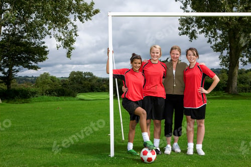 Preview: Female Soccer Players With A Coach Standing At Goal Post And Posing For The Camera After Match.