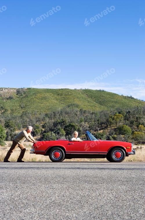 Preview: Vertical Profile Shot Of A Mature Man Pushing A Car Having Trouble With His Wife At The Wheel On A