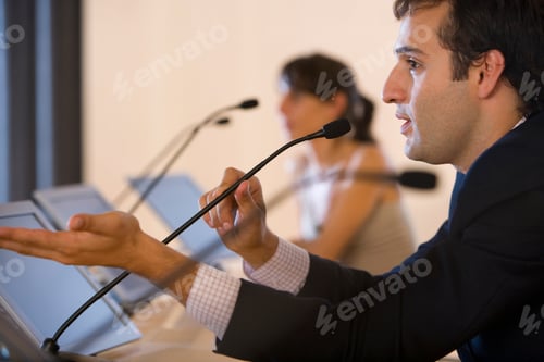 Preview: Horizontal Head And Shoulder Profile Shot Of A Businessman Speaking In Microphone At A Conference