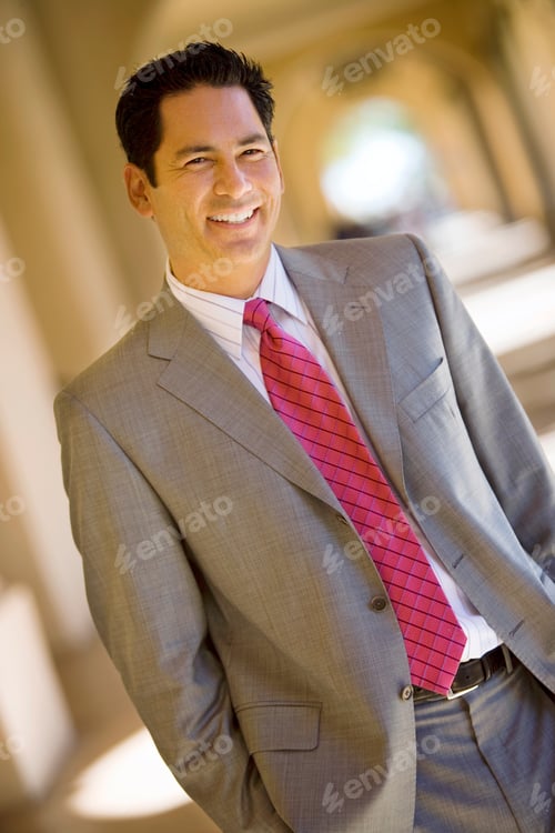 Preview: Vertical Tilted Shot Of A Businessman With A Pink Tie Smiles At The Camera In A Building Lobby.