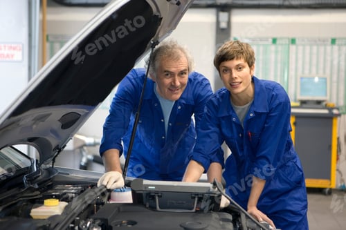 Preview: Senior Mechanic And His Colleague Posing With A Diagnostic Computer Placed On An Open Hood Of A