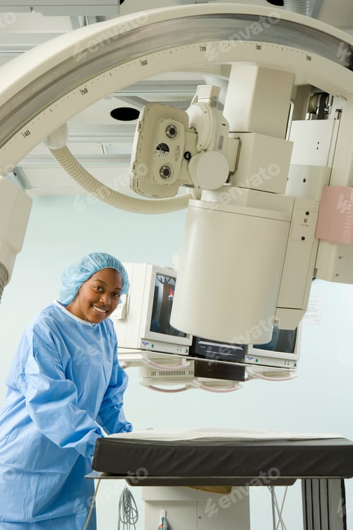 Preview: Portrait Of A Middle-Aged Doctor Standing In A Room With An X-Ray Machine And Smiling At The Camera