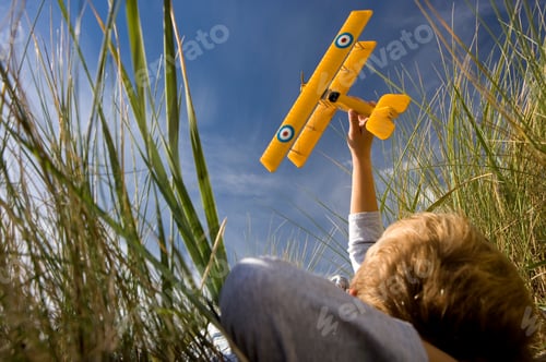 Preview: Horizontal Of A Little Boy Lying On The Grass In The Field And Holding Up A Toy Airplane On A