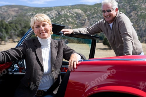 Preview: Horizontal Shot Of A Joyous Senior Couple Posing And Smiling At The Camera In A Red Convertible On