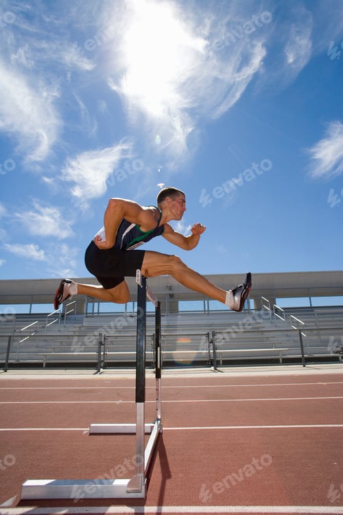 Preview: Side View Of A Male Athlete Jumping Over A Hurdle In The Race On Running Track