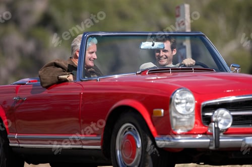 Preview: Horizontal Shot Of A Joyous Senior Man With His Son Driving In A Red Convertible Car On A Sunny Day.