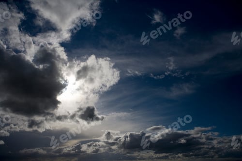 Preview: Natural Blue Sky With Fluffy Clouds Hiding The Sun Behind.