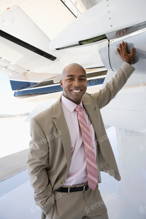 Preview: Vertical Shot Of A Smiling Businessman With Hand On An Airplane In The Hangar.