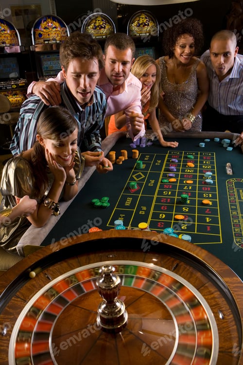 Preview: Group Of Men And Women Looking Excitedly At The Spinning Wheel While Playing Roulette At A Table In