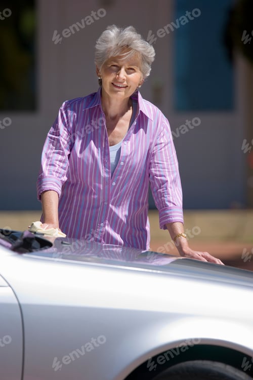Preview: Portrait Of A Senior Woman Polishing A Silver Car Parked On The Driveway In Front Of The House.