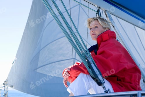 Preview: Low Angle View Of A Mature Woman In Red Jacket Sitting On The Deck Of The Sailing Boat Below Sail.