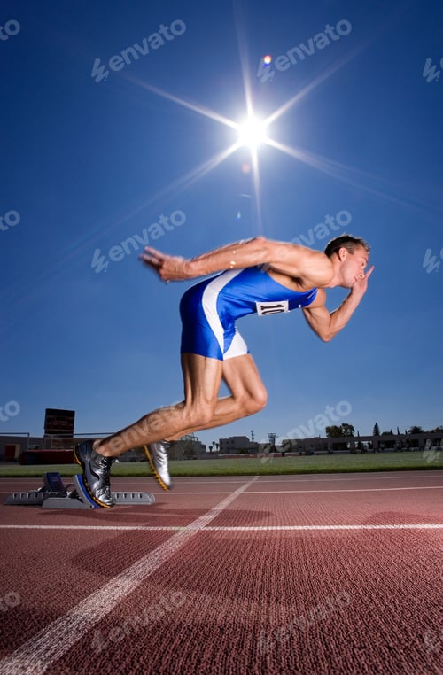 Preview: Vertical Shot Of A Young Male Sprinter Setting Off From His Starting Blocks At An Athletics Event