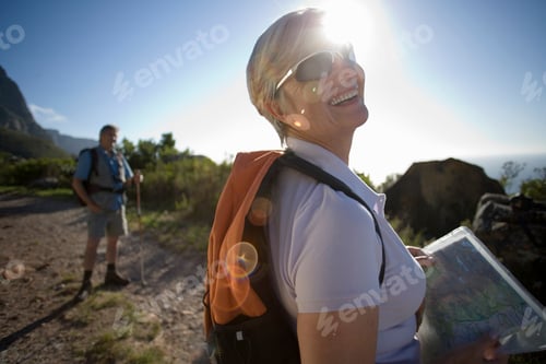 Preview: Horizontal Waist Up Profile Shot Of A Smiling Mature Woman Looking At A Map On A Mountain Trail