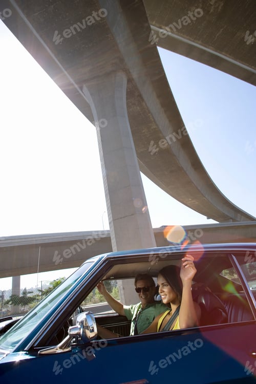 Preview: Vertical Shot Of A Young Couple In The Car Beneath An Overpass On A Bright Sunny Day.