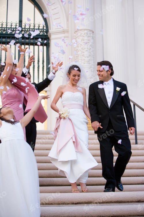 Preview: Vertical Shot Of A Smiling Bride And Groom Descending Steps Outside The Church While The Wedding