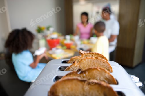 Preview: Horizontal Shot With Selective Focus On Bread In The Toaster With Family Of Four At A Breakfast