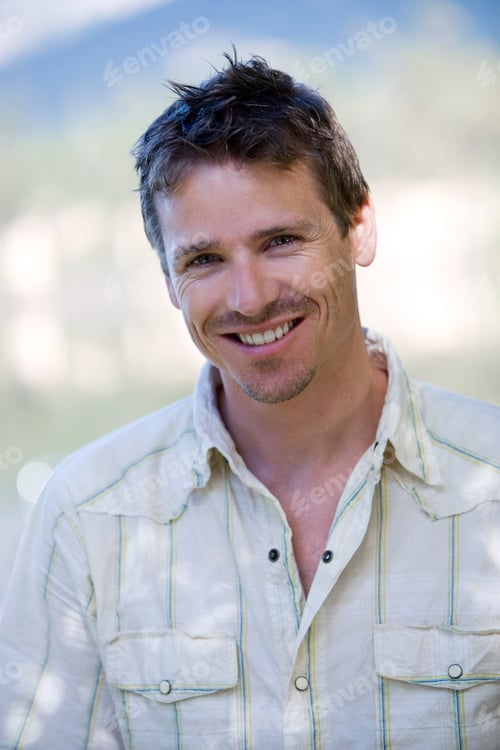 Preview: Vertical Portrait Of A Man Wearing A White Shirt With Open Collar Smiles At The Camera.