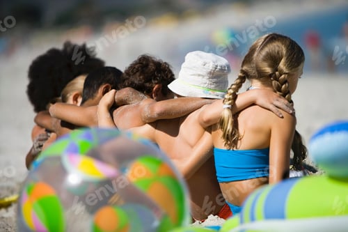 Preview: Rear View Of Children Sitting On A Beach With Arms Over Each Others Shoulder With Selective Focus