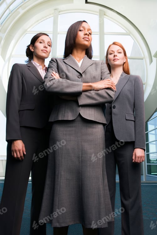 Preview: Vertical Low Angle Portrait Of Three Powerful Businesswoman In Grey Suits Look At The Camera With